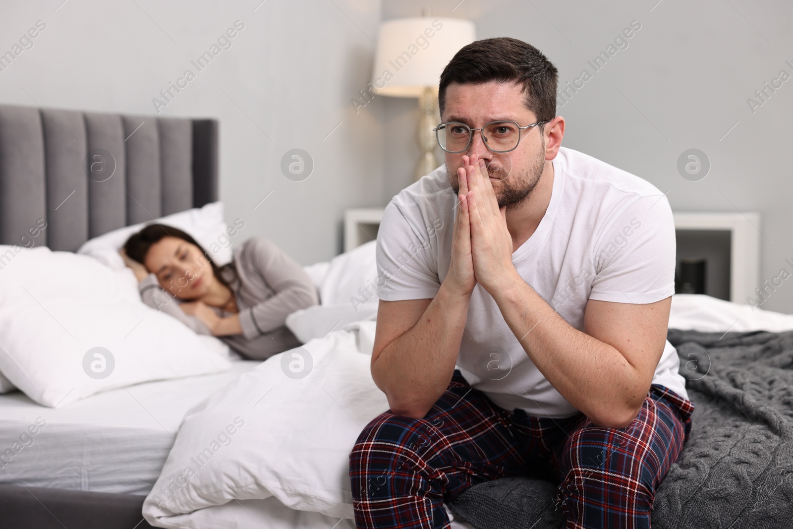 Photo of Stressed husband after quarrel with his wife in bedroom, selective focus. Relationship problems