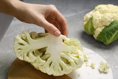 Photo of Woman with half of fresh cauliflower at light grey table, closeup