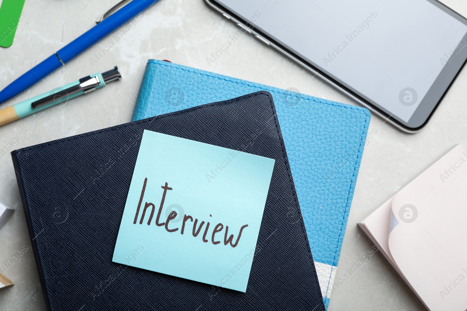 Photo of Reminder note about job interview and stationery on table, flat lay