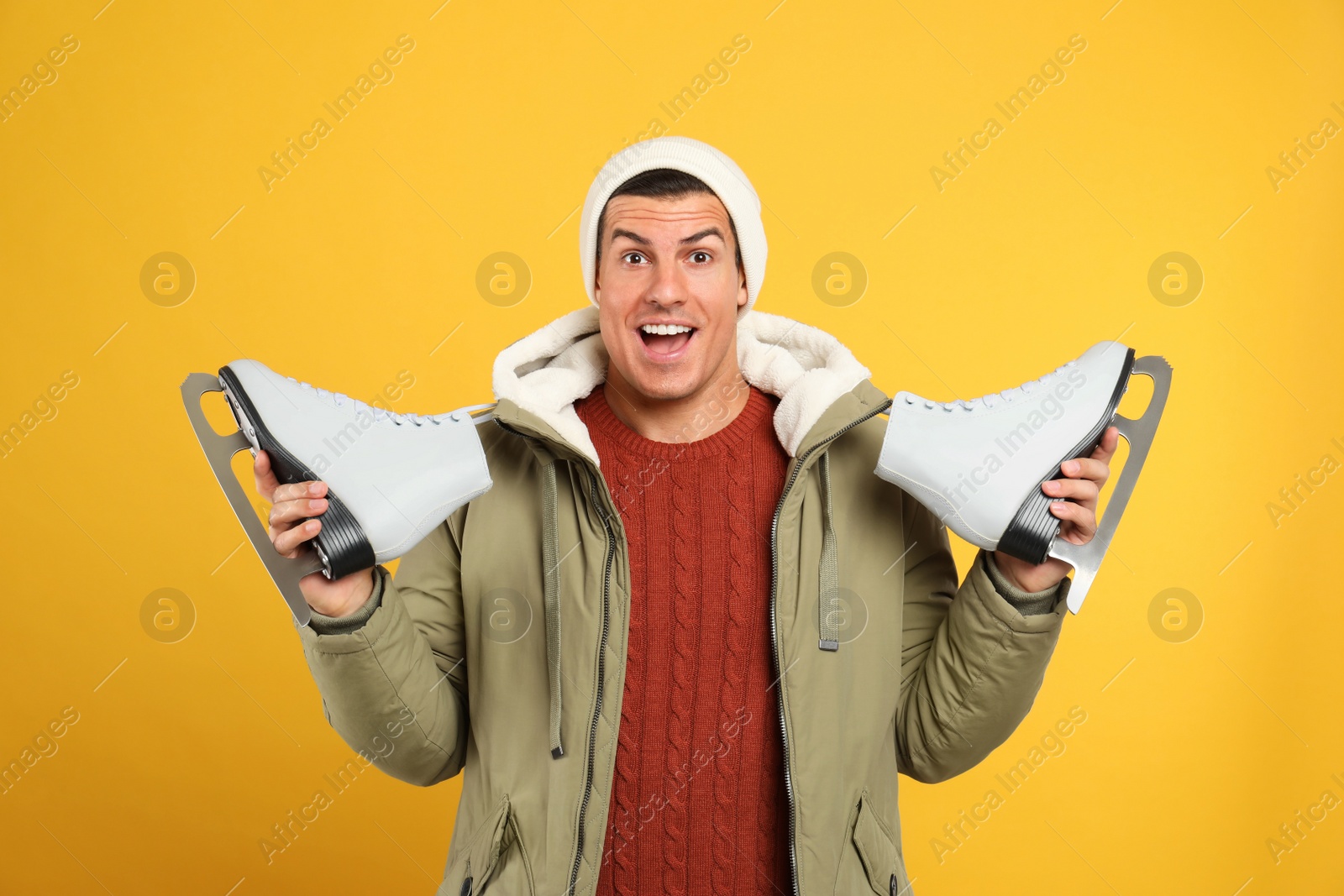 Photo of Emotional man with ice skates on yellow background