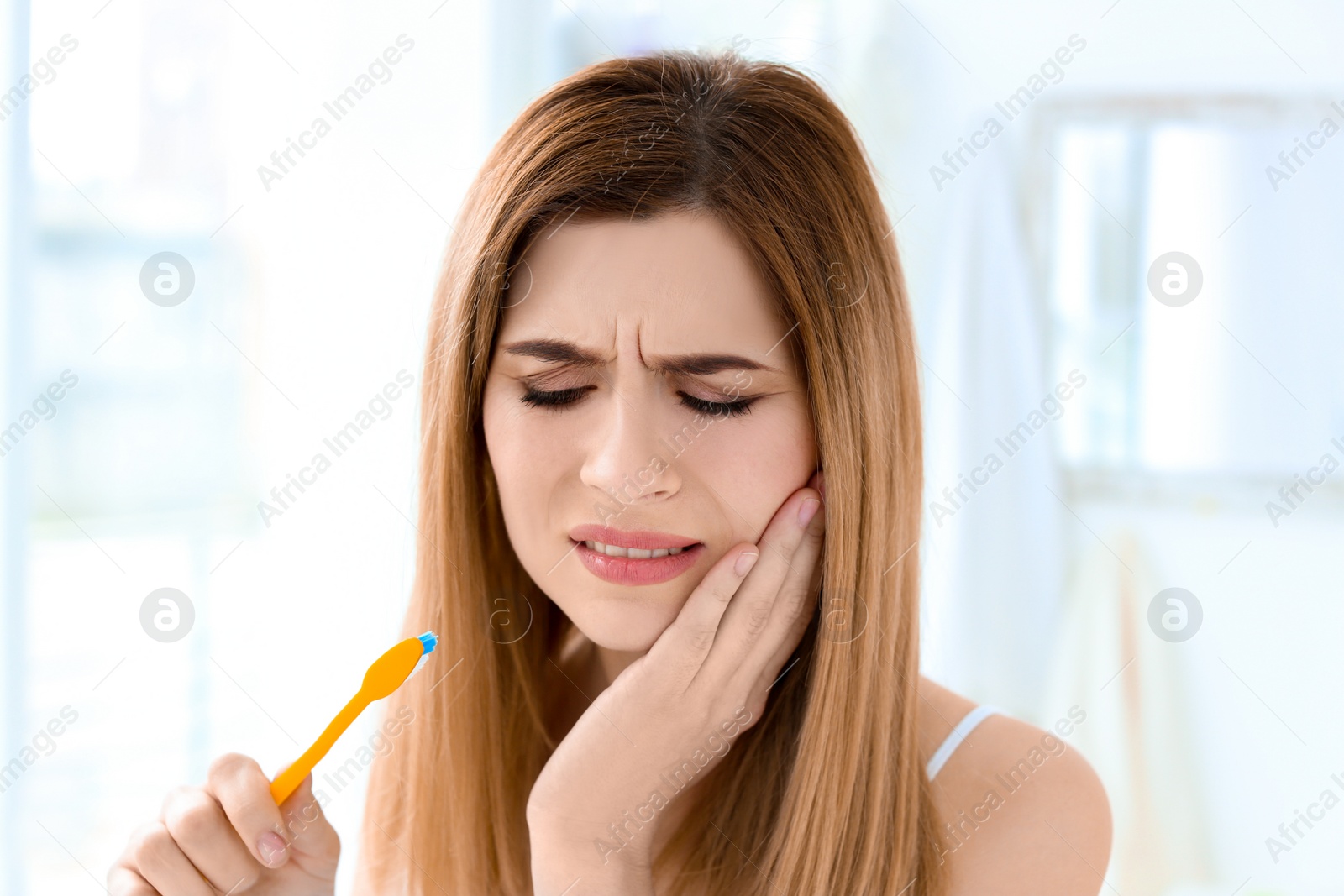 Photo of Young woman suffering from toothache indoors