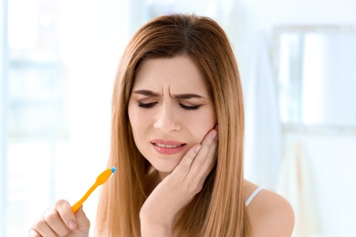 Young woman suffering from toothache indoors