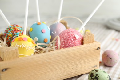 Delicious sweet cake pops in wooden crate on table, closeup. Easter holiday