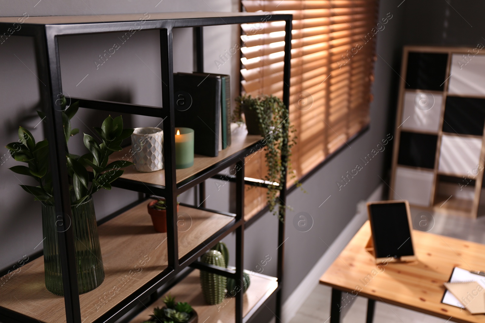 Photo of Shelving with different decor, books and houseplants near gray wall in room. Interior design