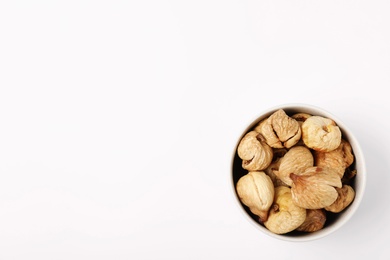 Photo of Bowl of dried figs on white background, top view with space for text. Healthy fruit