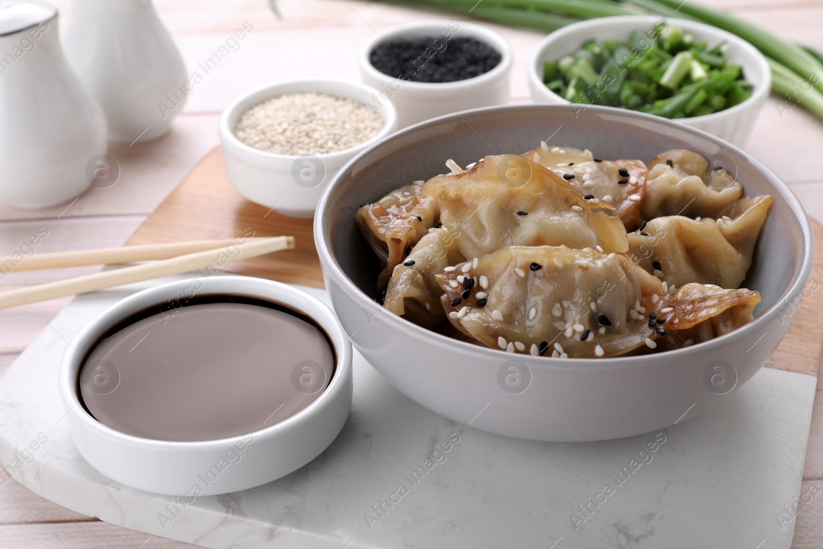 Photo of Delicious gyoza (asian dumplings) with sesame and soy sauce on table, closeup