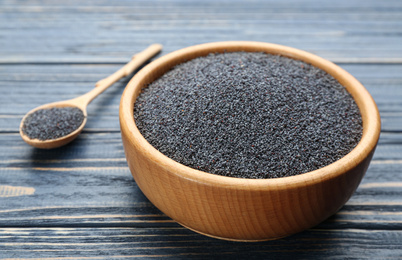 Photo of Poppy seeds in bowl on blue wooden table