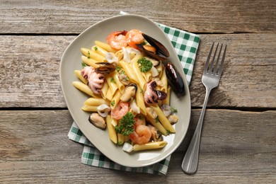 Photo of Delicious pasta with sea food served on wooden table, flat lay
