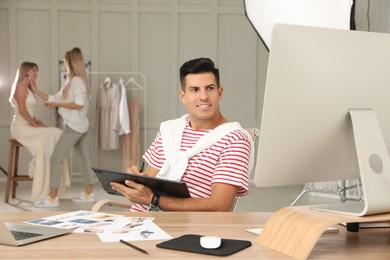 Photo of Professional retoucher working with graphic tablet at desk in photo studio