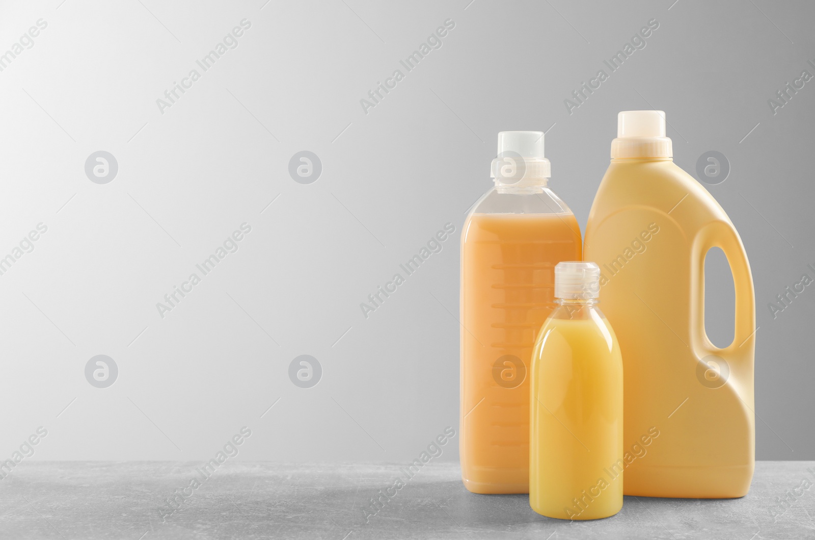 Photo of Different bottles with detergents on grey table, space for text