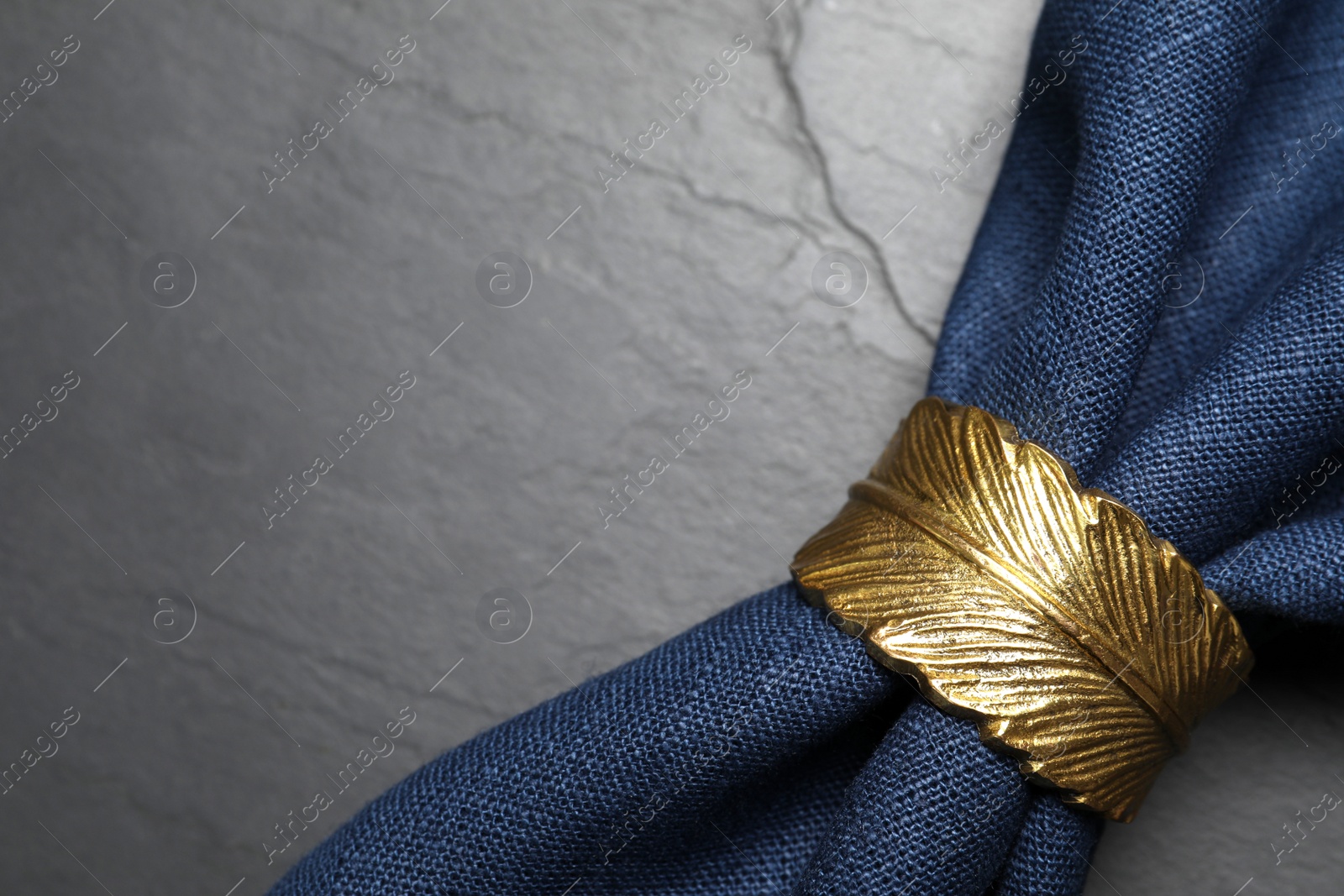 Photo of Blue fabric napkin with beautiful decorative ring on dark table, closeup. Space for text