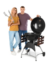 Happy couple with barbecue grill and utensils on white background