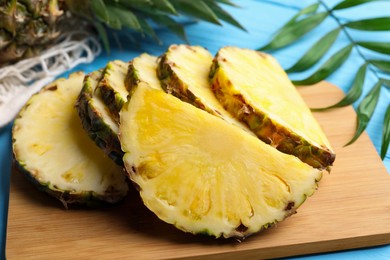 Slices of ripe juicy pineapple and green leaf on light blue table, closeup