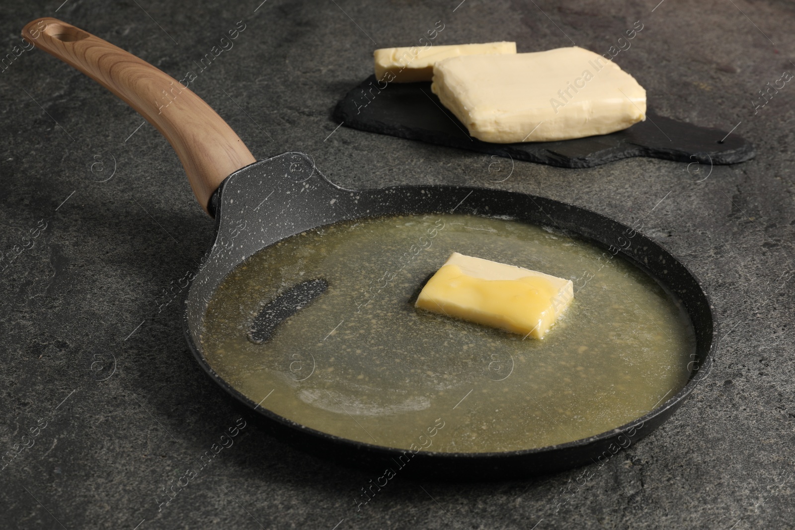 Photo of Melting butter in frying pan on grey table