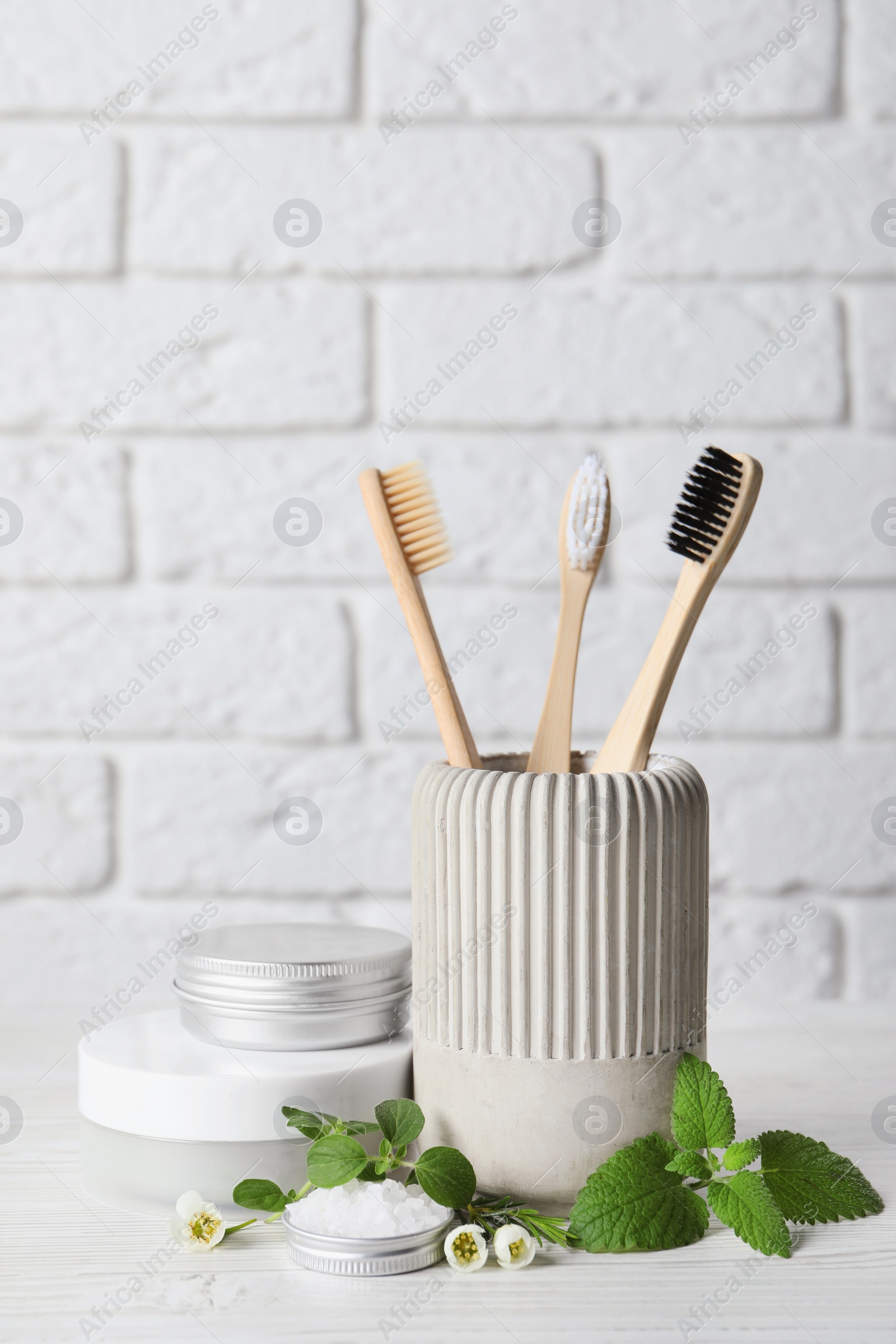 Photo of Toothbrushes, dental products and herbs on white wooden table