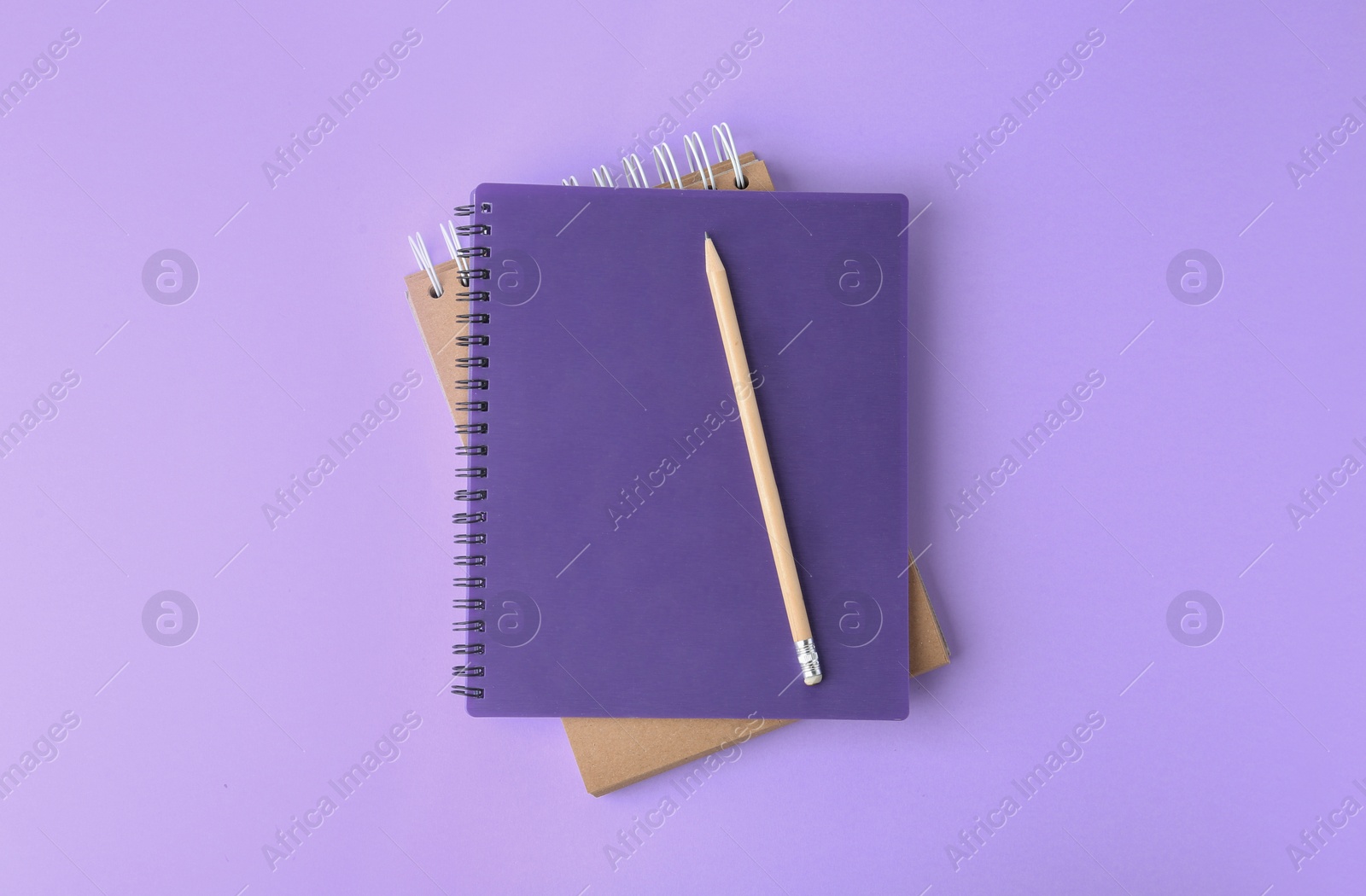 Photo of Notebooks with pencil on lilac background, top view