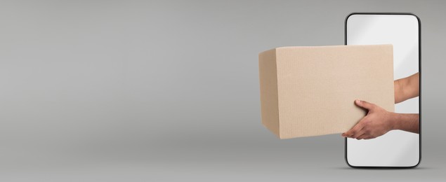 Image of Courier passing parcel through smartphone on grey background. Delivery service. Banner design with space for text