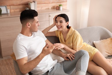 Happy couple in pyjamas spending time together on sofa at home