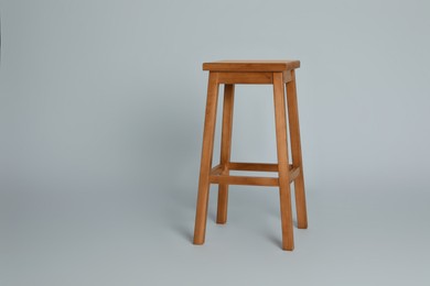 Stylish wooden stool on light grey background. Space for text