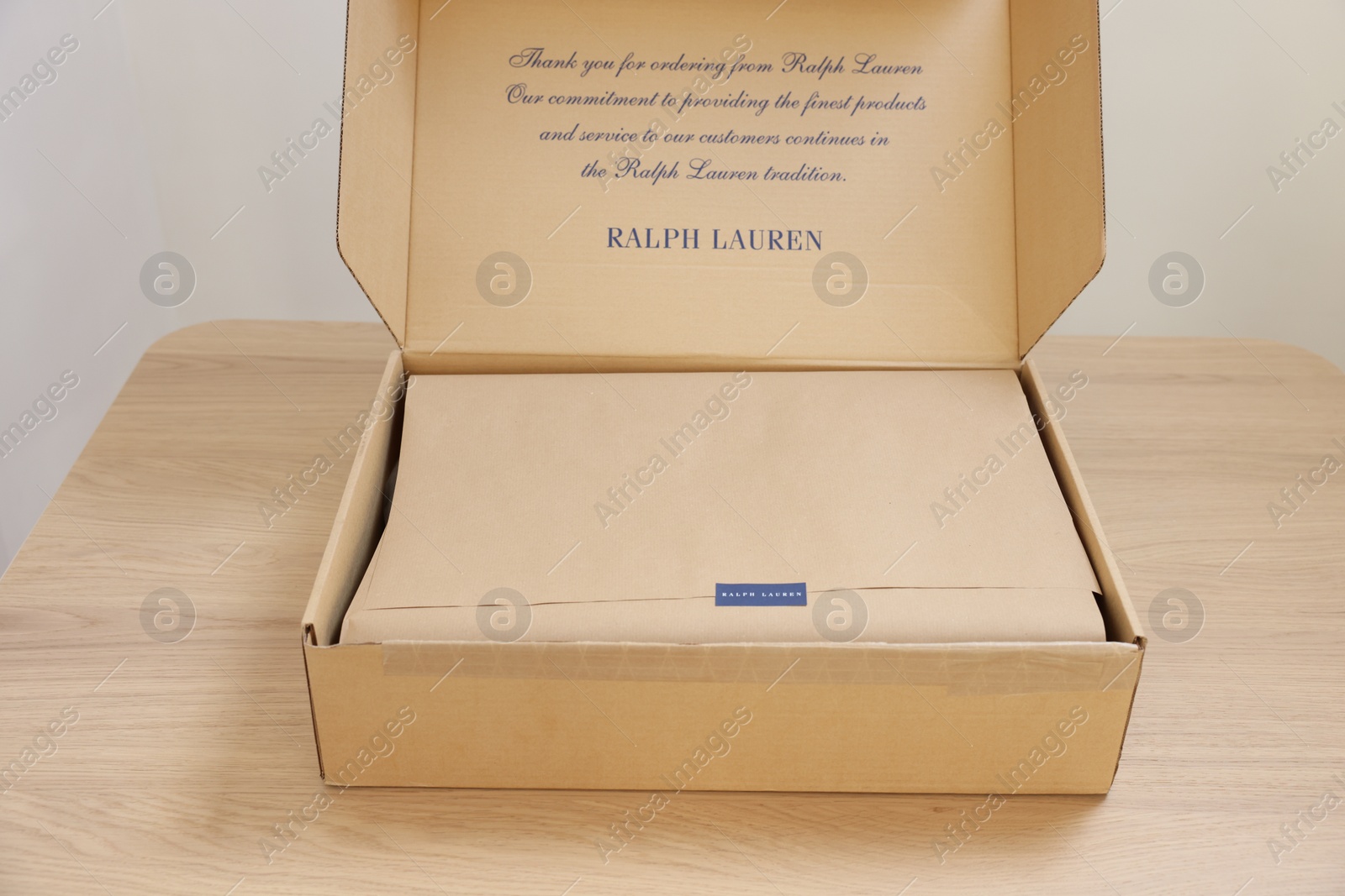 Photo of Leiden, Netherlands - December 6, 2023: Open box with Ralph Lauren garment on wooden table