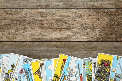 Photo of Tarot cards on wooden table, top view. Space for text