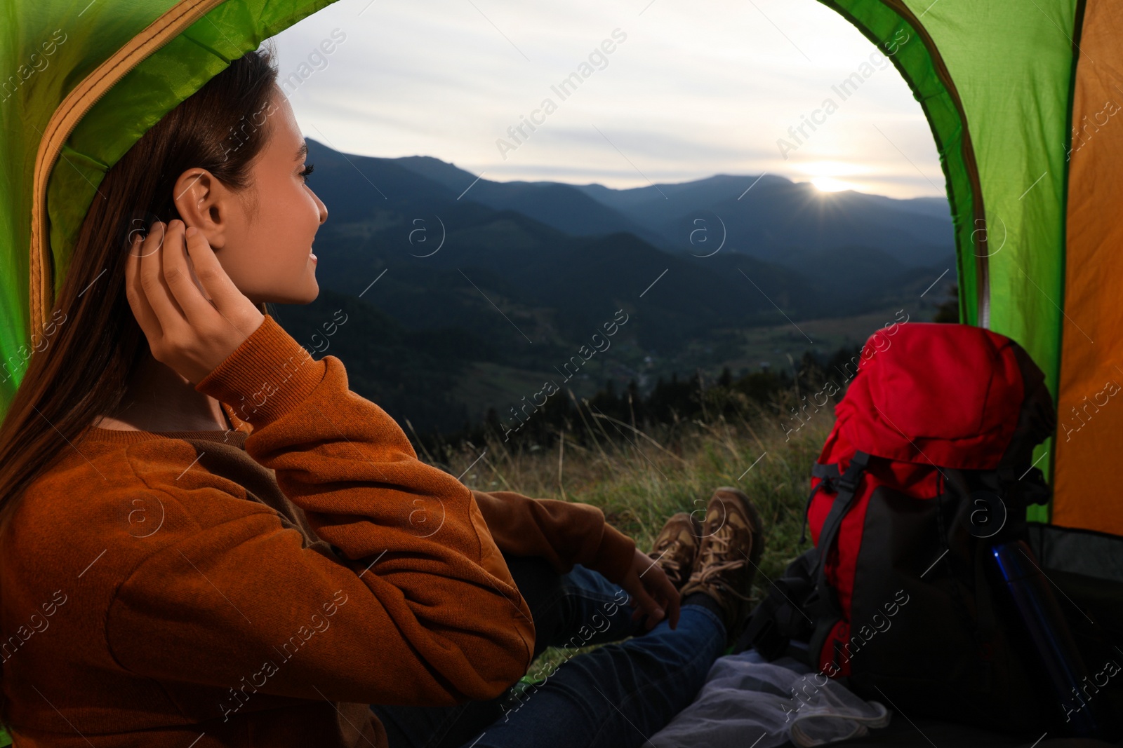 Photo of Young woman enjoying mountain landscape in camping tent, view from inside