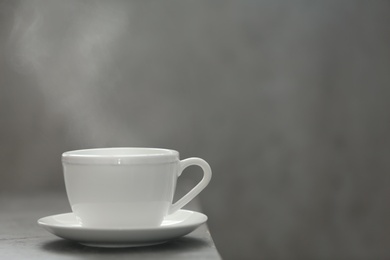 Photo of Cup of tea and saucer on table against gray background