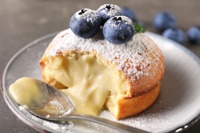 Photo of Tasty vanilla fondant with white chocolate and blueberries on grey table, closeup