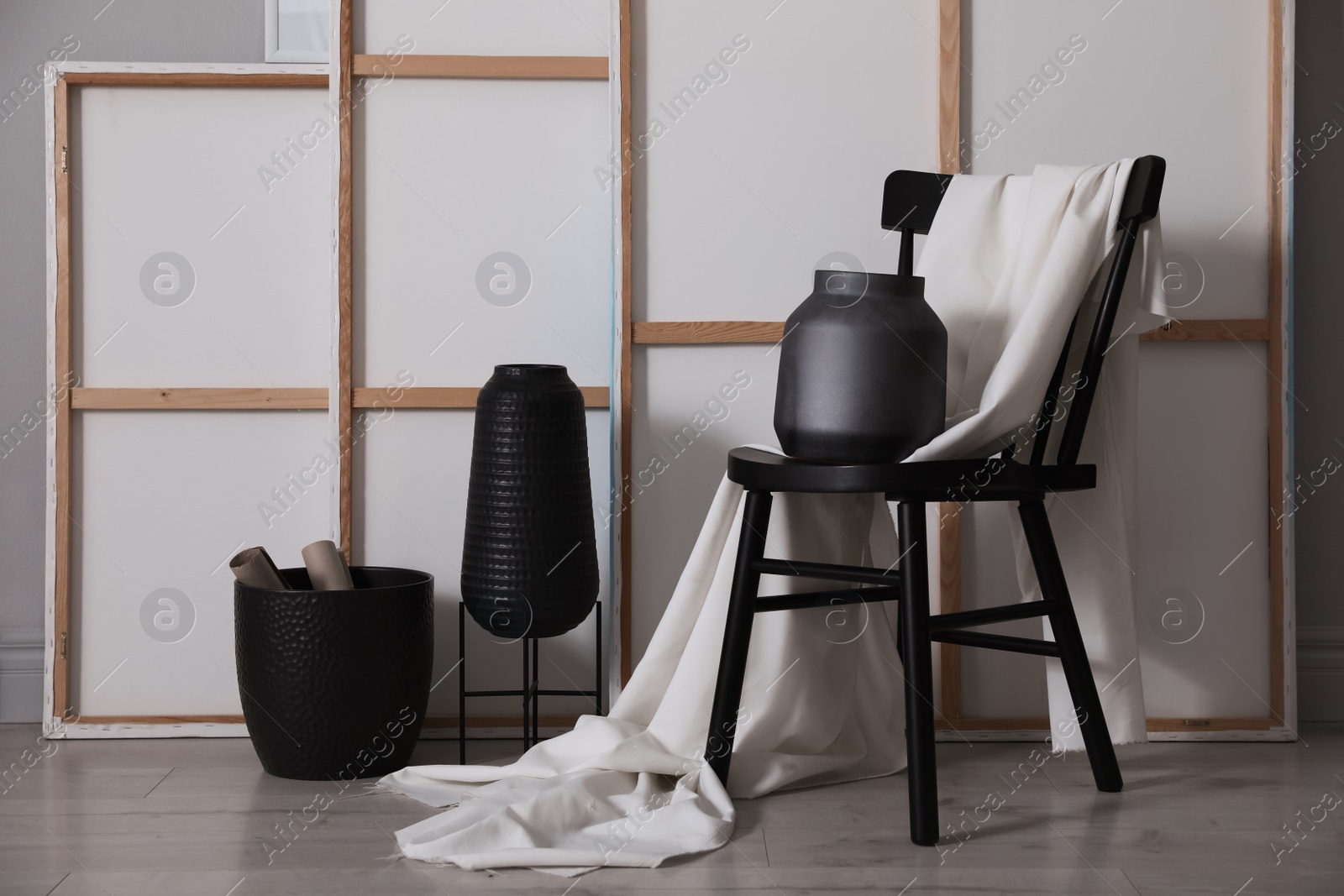 Photo of Chair with white fabric and vase near paintings in artist's studio