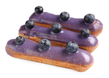 Photo of Delicious eclairs decorated with blueberries isolated on white