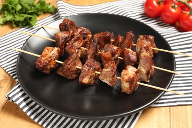 Photo of Plate with delicious shish kebabs on wooden table