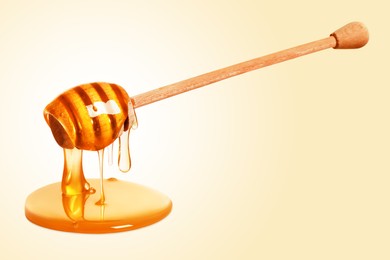 Natural honey dripping from dipper on beige background