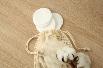 Photo of Cotton pads, bag and flowers on wooden table, top view