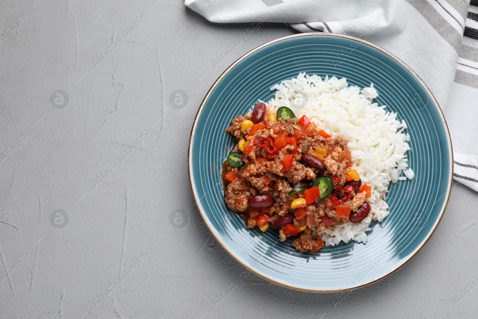 Photo of Plate of rice with chili con carne on light grey table, flat lay. Space for text