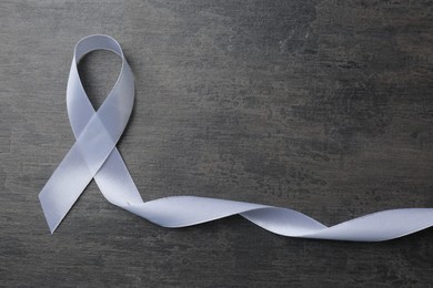 White awareness ribbon on grey table, top view. Space for text