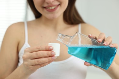 Photo of Young woman using mouthwash on blurred background, closeup