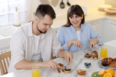 Happy couple having tasty breakfast at home