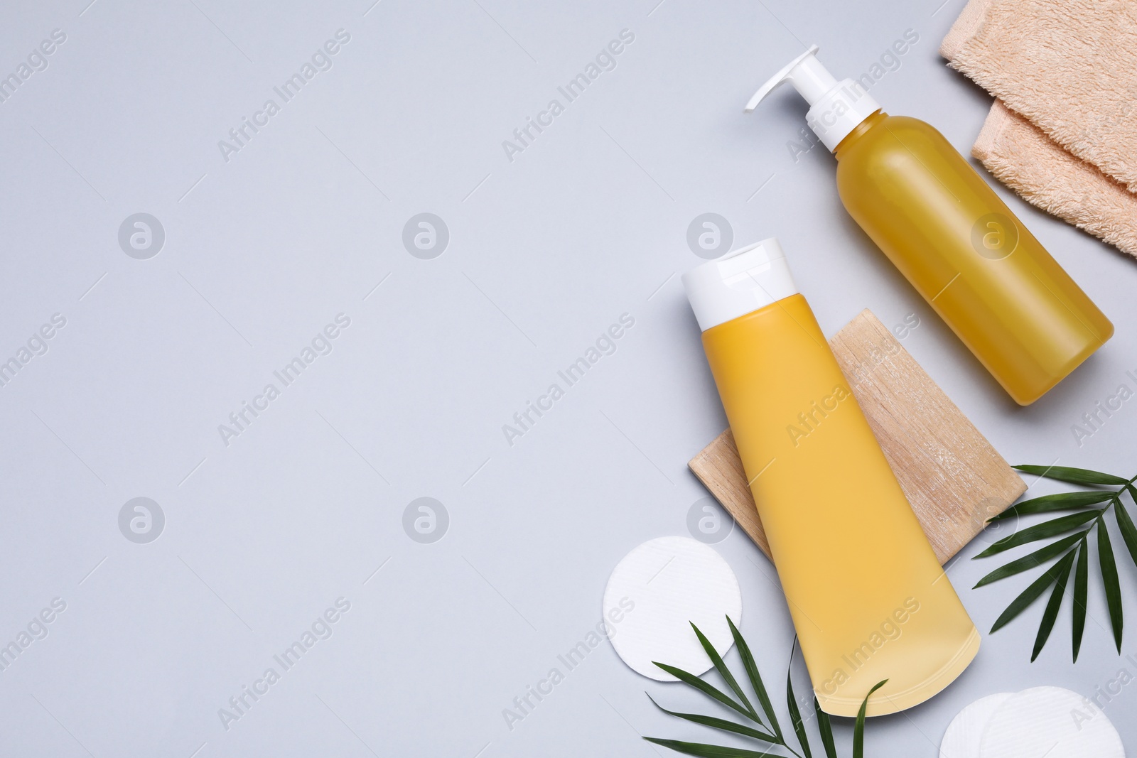 Photo of Different cleansers, leaves, and cotton pads on light grey background, flat lay with space for text. Cosmetic product