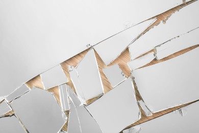Photo of Shards of broken mirror on wooden background, top view