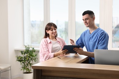 Smiling medical assistant working with patient at hospital reception