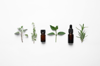 Photo of Bottles of essential oils and different herbs on white background, flat lay