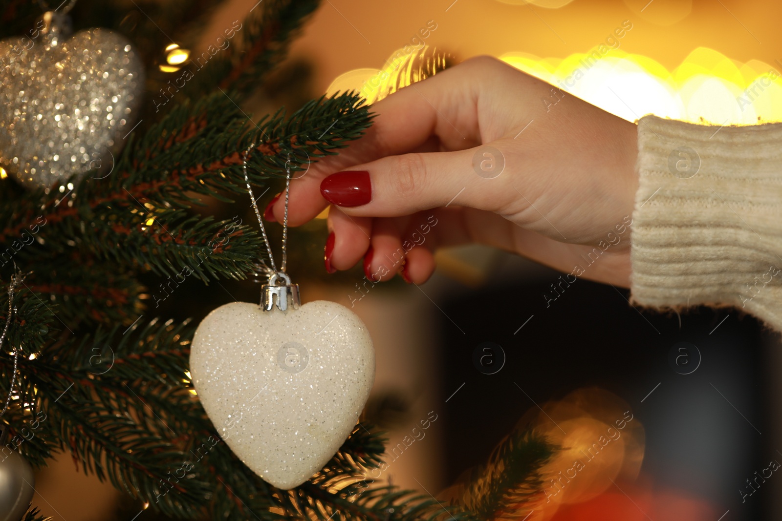 Photo of Woman decorating Christmas tree at home, closeup