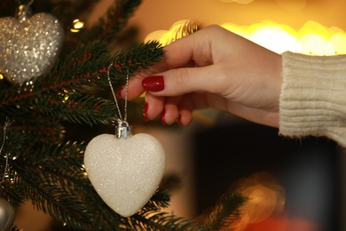 Photo of Woman decorating Christmas tree at home, closeup