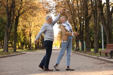 Photo of Affectionate senior couple dancing together in autumn park