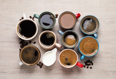 Photo of Many different cups of coffee and milk on white wooden table, flat lay