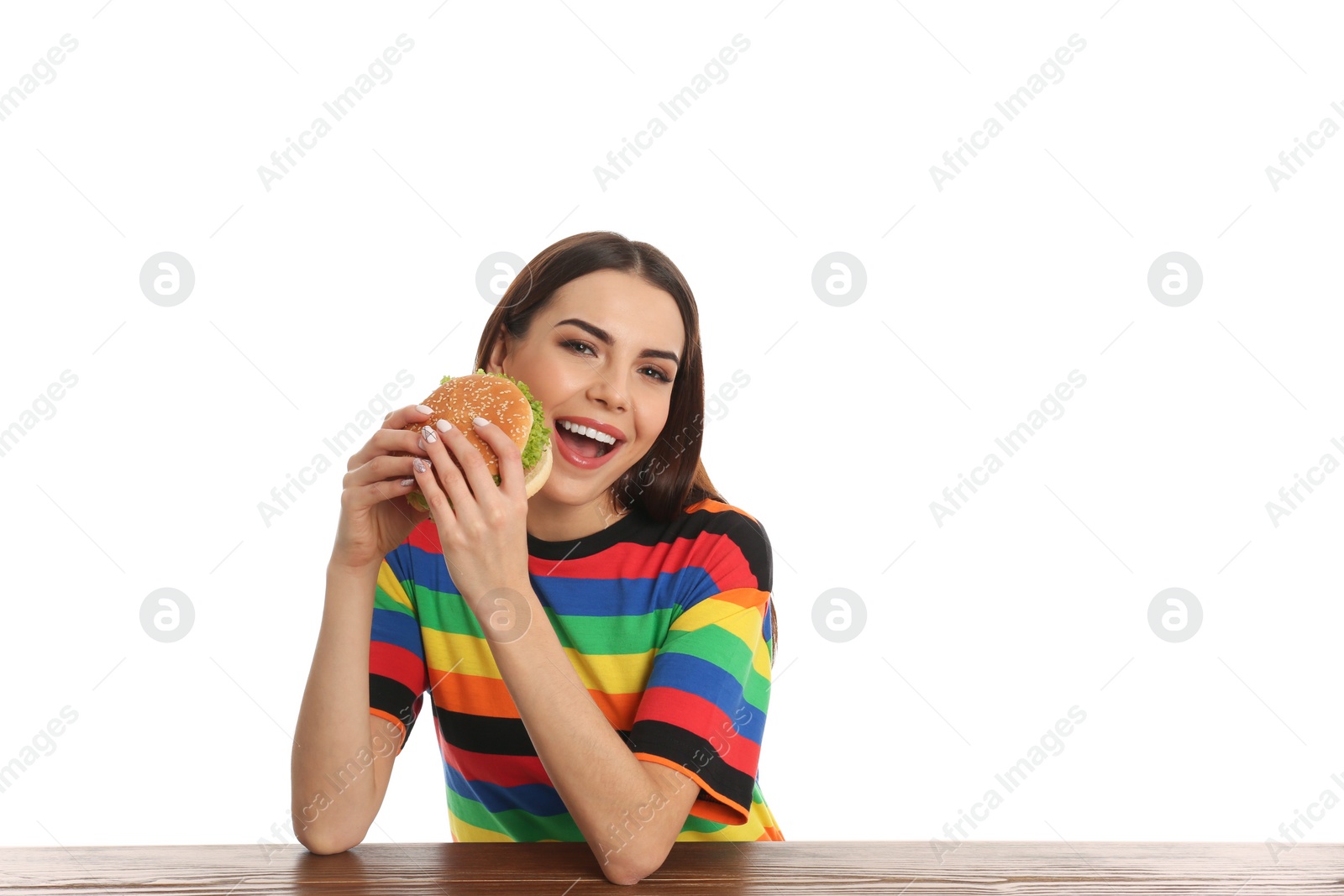 Photo of Young woman eating tasty burger at table on white background