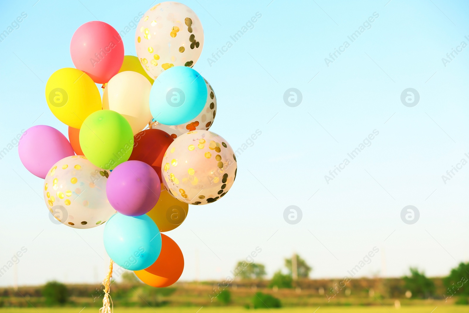 Photo of Many colorful balloons against blue sky on sunny day