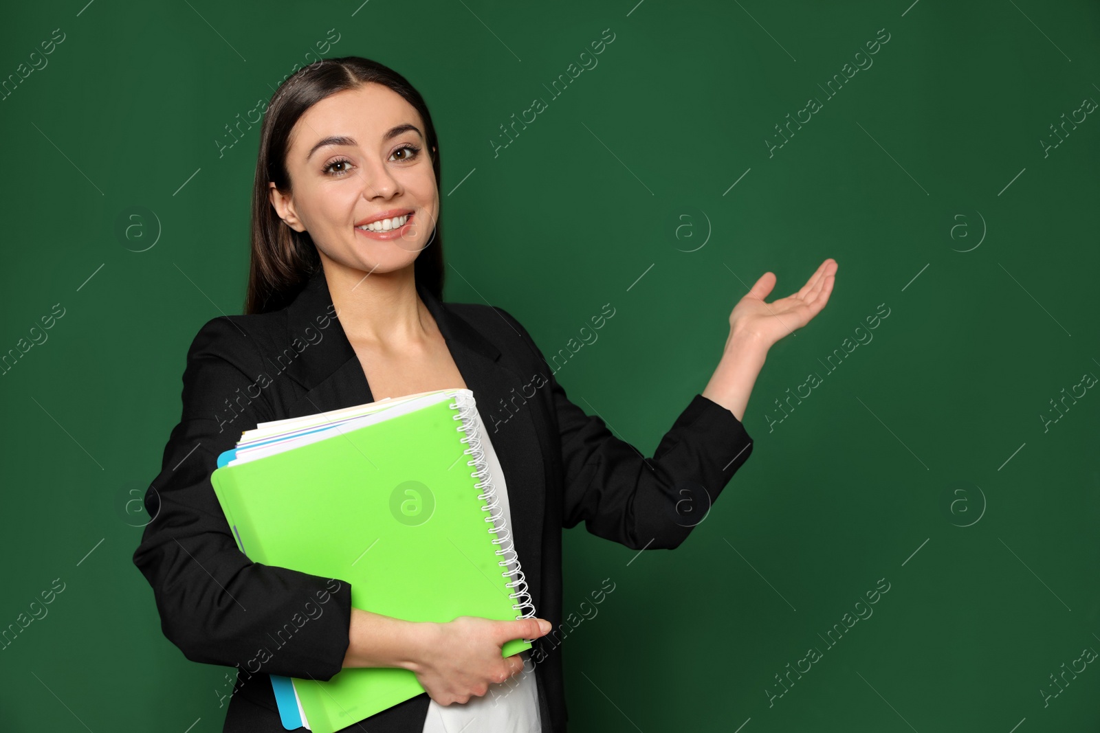 Photo of Portrait of young teacher with notebooks on green background