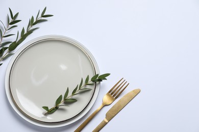 Stylish setting with cutlery and eucalyptus leaves on white background, top view. Space for text