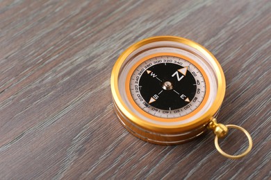 Photo of One compass on wooden table, closeup. Space for text